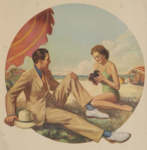 Man and woman sit on a beach, camera
